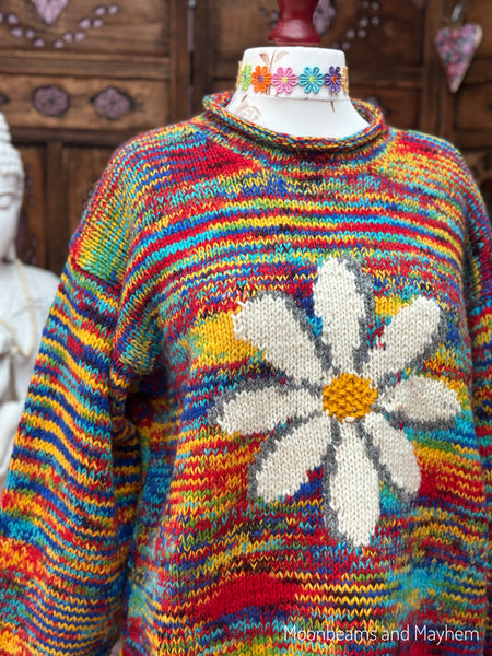 Angled close-up showing the daisy motif, dropped shoulder and colourful handmade wool knit