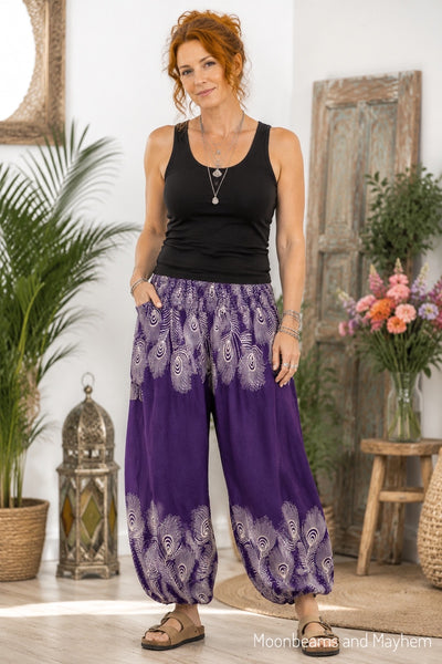 Red-haired woman wearing purple peacock harem trousers with a black vest and sandals